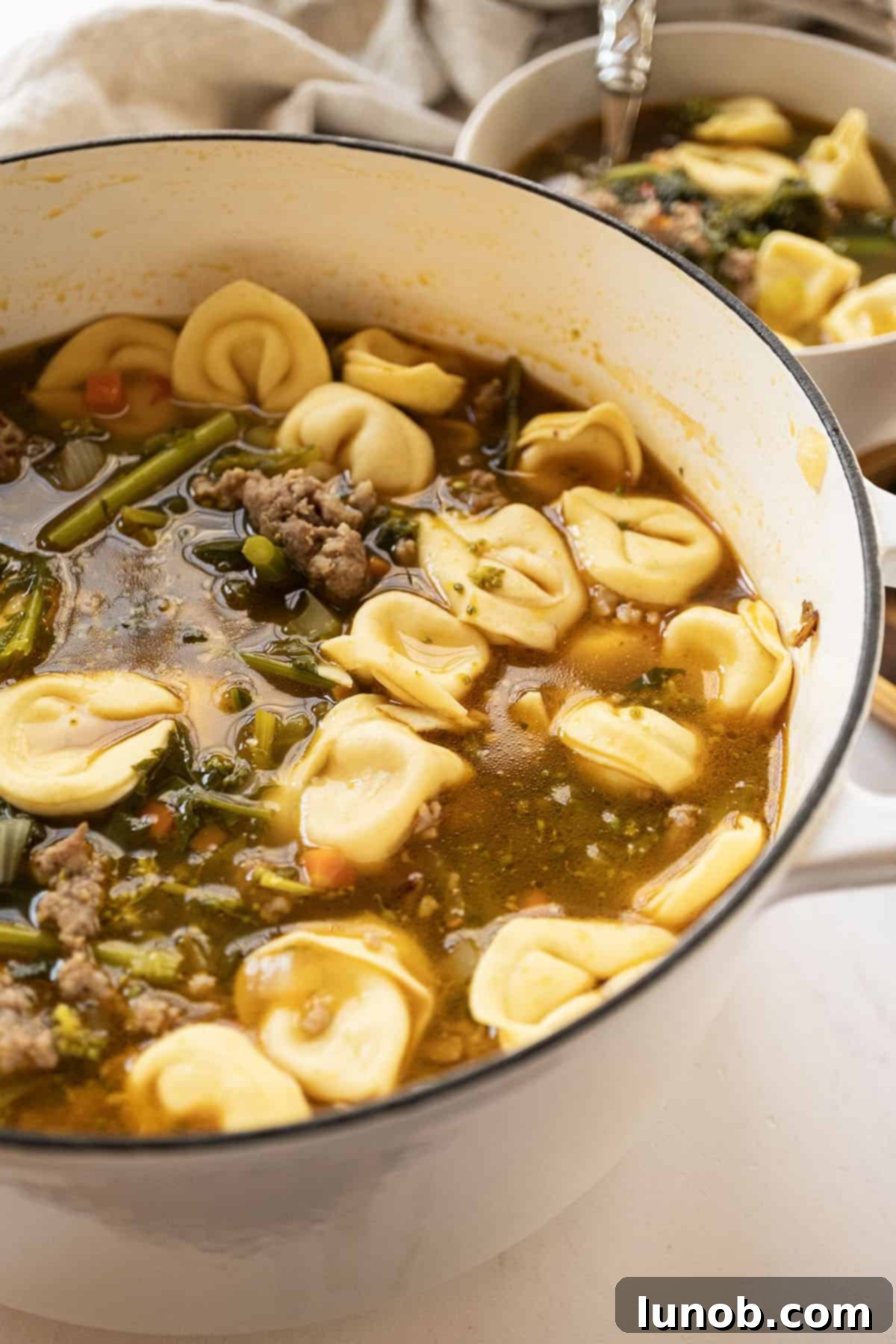 Sausage and broccoli rabe soup with tortellini in a dutch oven.