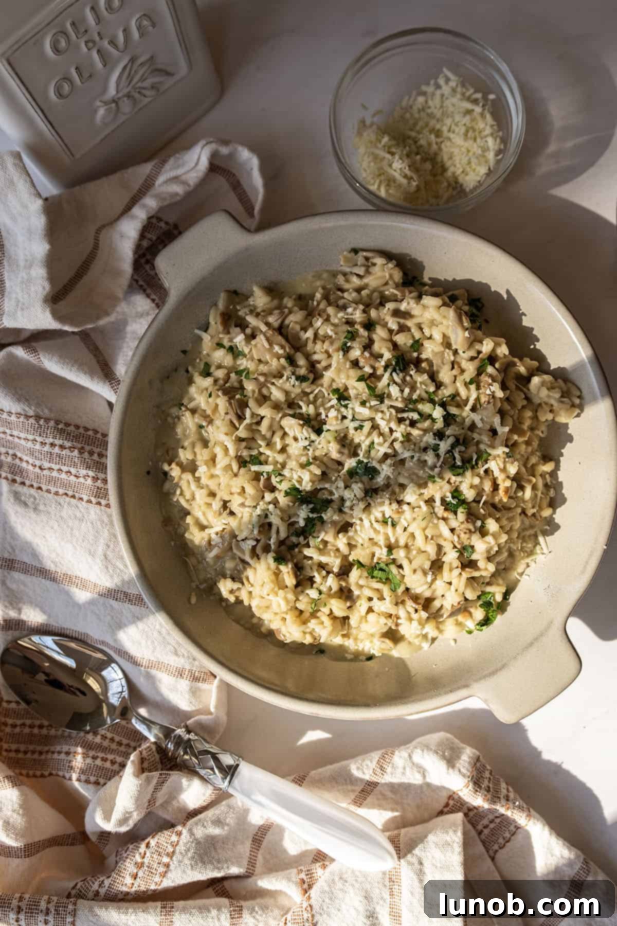 A bowl of risotto with mushrooms topped with extra gorgonzola and parsley.