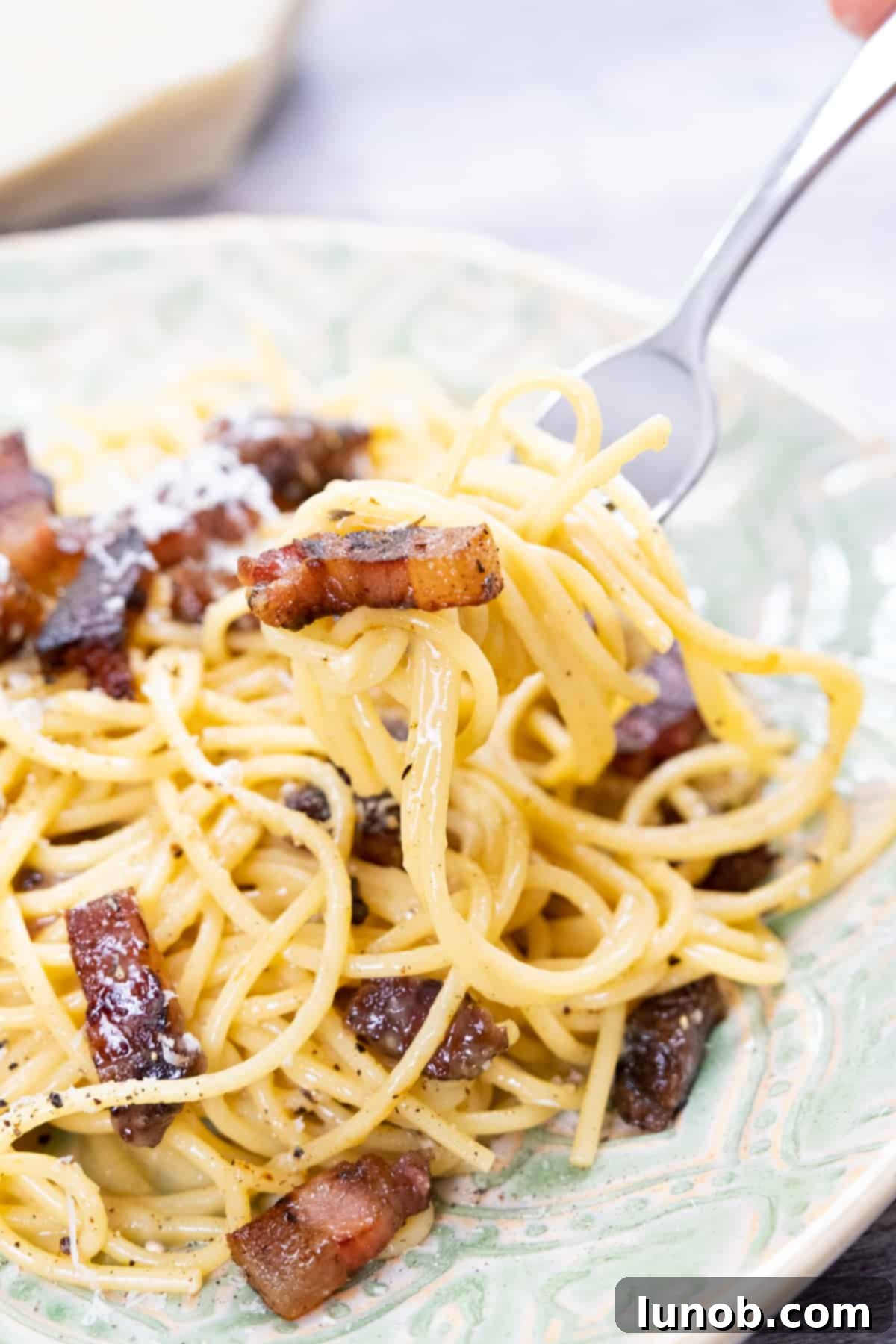 The Art of Perfect Carbonara 2 Authentic spaghetti carbonara with crispy guanciale, topped with black pepper and freshly grated pecorino romano.