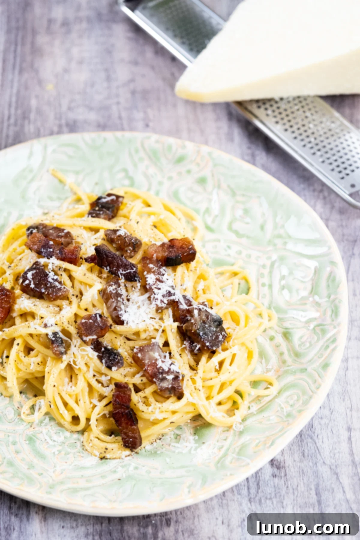 The Art of Perfect Carbonara 12 Authentic carbonara served on a plate with fresh pecorino romano and crispy guanciale, ready to be enjoyed.