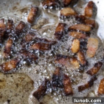 The Art of Perfect Carbonara 5 Guanciale frying in its own rendered fat in a saucepan, cooking evenly.