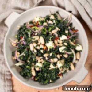 Kale and Cannellini Bean salad in a bowl topped with pine nuts.