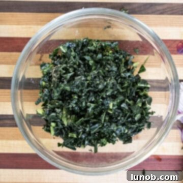 Finely chopped and massaged kale leaves placed in a bowl, ready for the other salad ingredients.