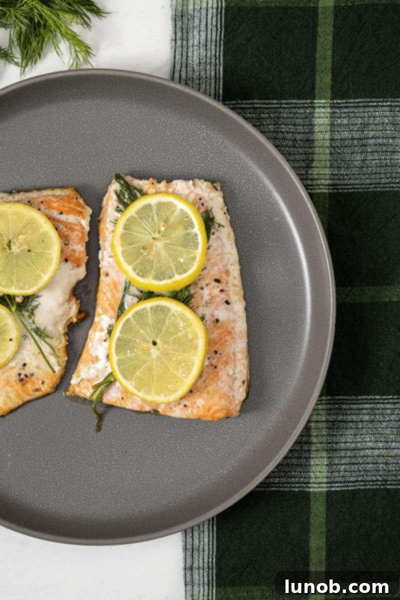 Crispy skin lemon dill salmon cooked in a cast iron pan, garnished with fresh herbs