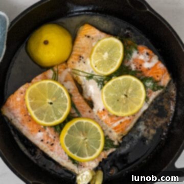 Basted salmon in a cast iron pan, ready to be transferred to the oven.