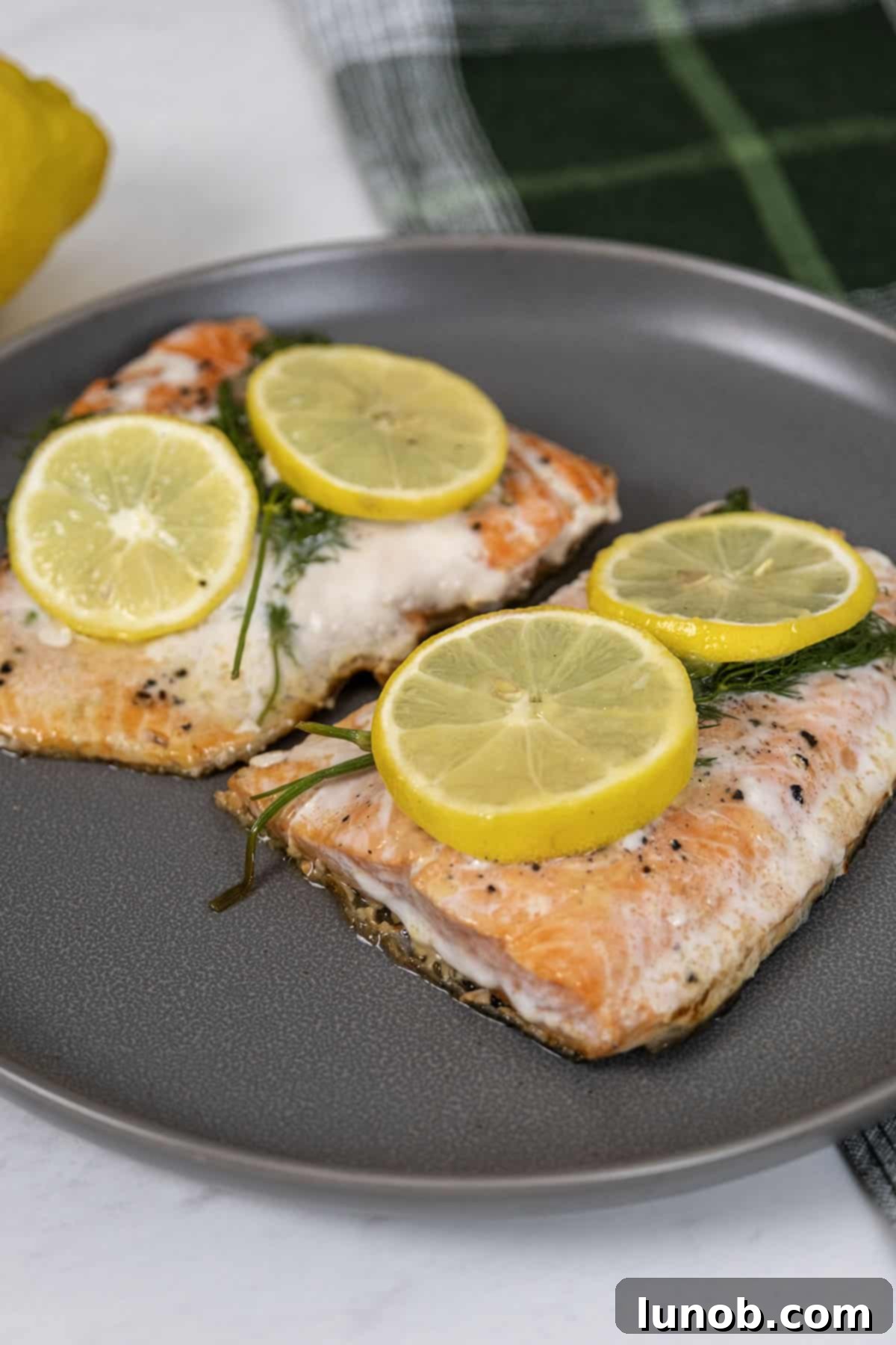 Close-up of perfectly cooked cast iron lemon dill salmon, showing moist flesh and crispy skin.