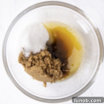 Soft Baked White Chocolate Macadamia Delights 6 Brown butter combined with white and brown sugar in a mixing bowl.