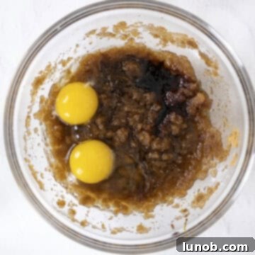 Soft Baked White Chocolate Macadamia Delights 7 All wet ingredients combined in a bowl, including egg, egg yolk, vanilla, almond extract, and molasses.