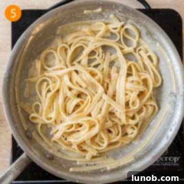 Traditional Roman Fettuccine Alfredo 8 Grated Parmigiano cheese being added to the pasta in the pan, off the heat.