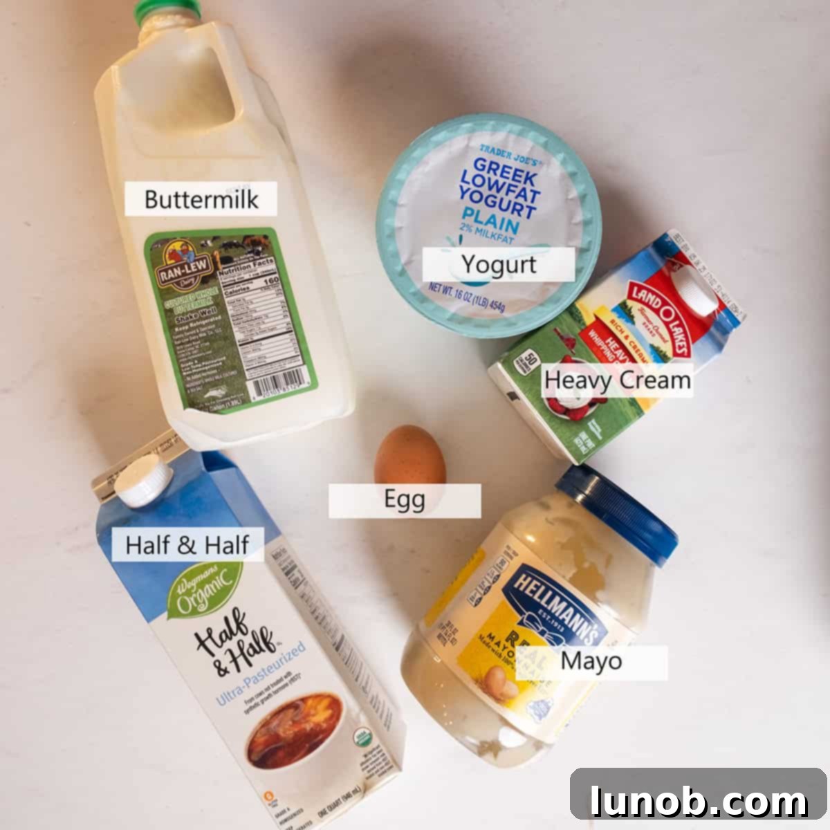 A selection of bowls containing different battering options: heavy cream, buttermilk, mayonnaise, yogurt, and half and half, ready for frying chicken.