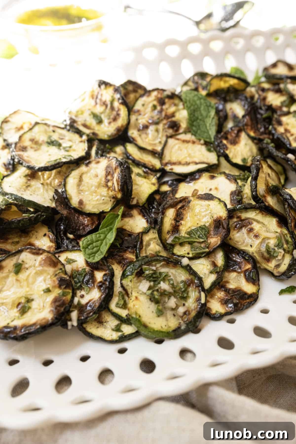 Minty Marinated Zucchini 2 Crispy grilled Zucchini alla Scapece on a tray, elegantly garnished with fresh mint leaves.