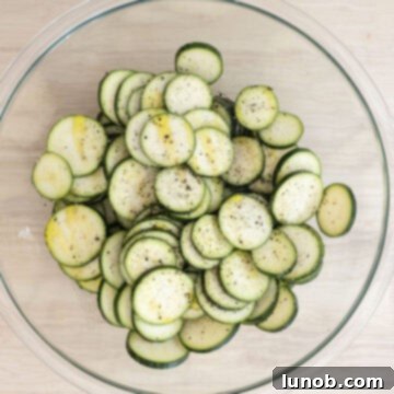 Minty Marinated Zucchini 6 Zucchini slices in a large bowl, drizzled with olive oil and seasoned generously with salt and pepper, ready for grilling.