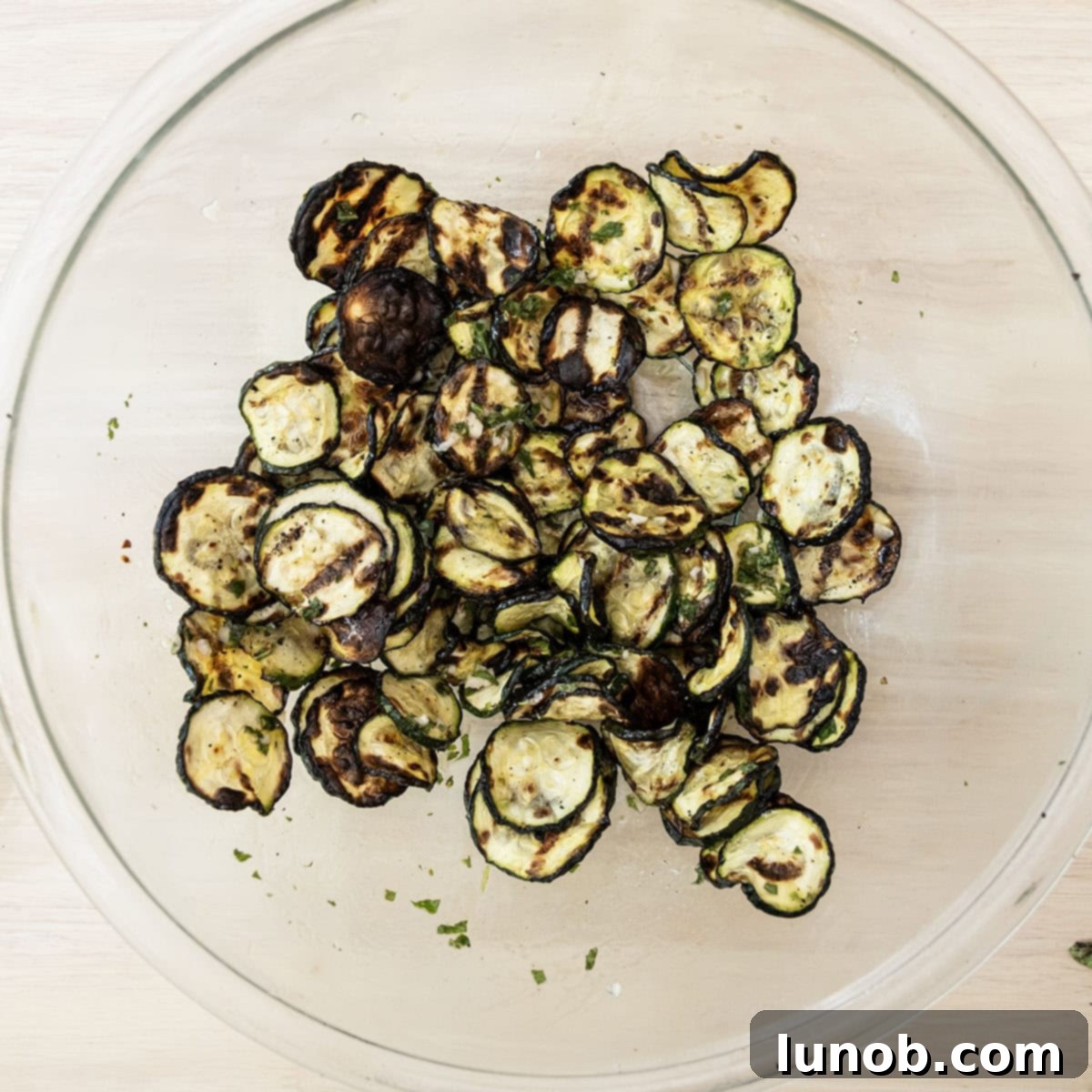 Minty Marinated Zucchini 8 Grilled zucchini in a large bowl, being tossed vigorously with the fresh mint dressing until fully coated.