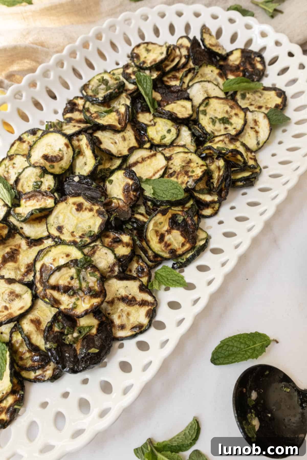 Minty Marinated Zucchini 9 A serving tray filled with vibrant Zucchini alla Scapece, garnished generously with fresh mint for a stunning presentation.
