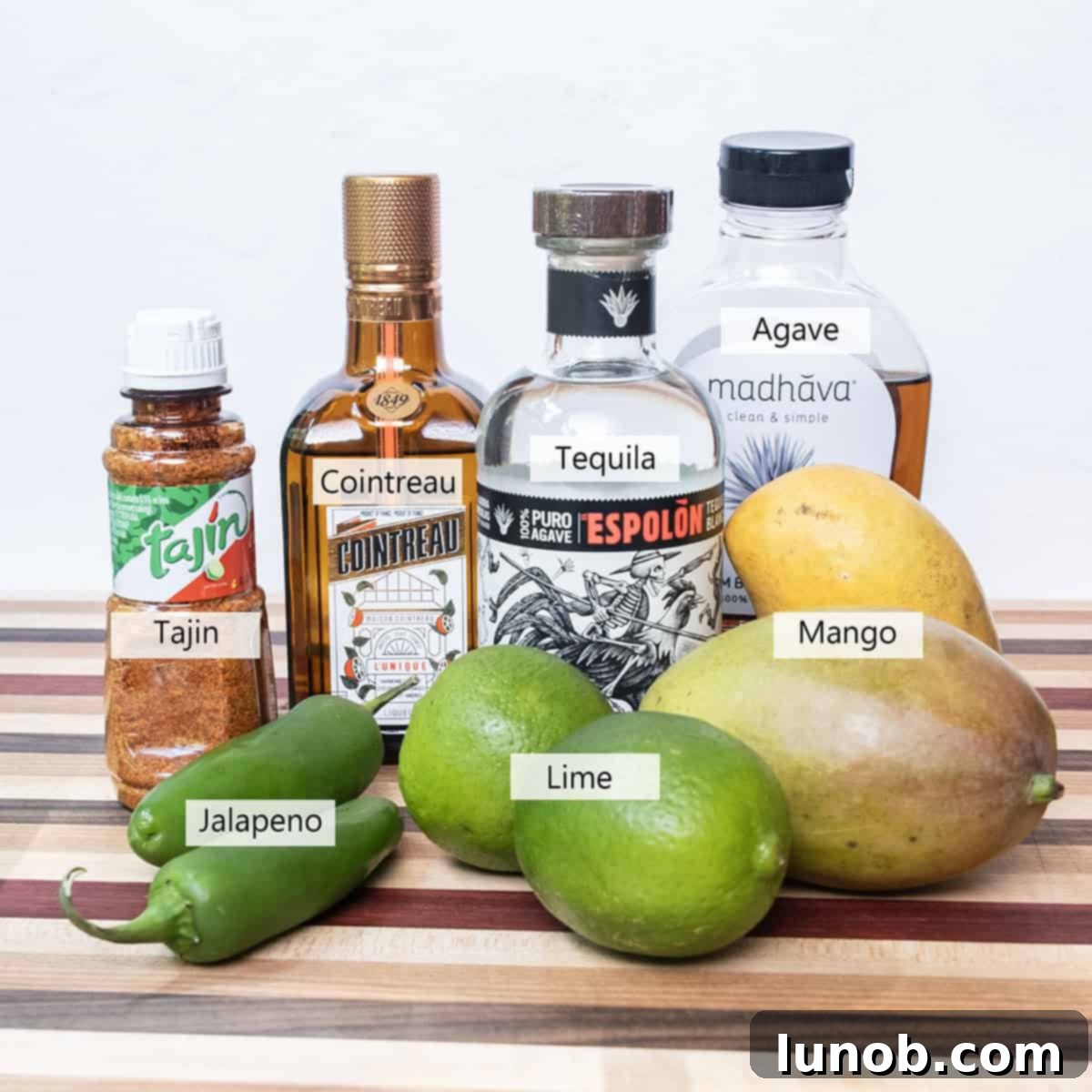 Sizzling Mango Margarita 3 All the fresh ingredients laid out for making the spicy mango margarita, including tequila, mango, limes, jalapenos, and a bottle of Cointreau.