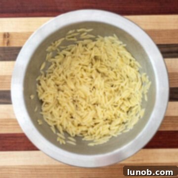 Vibrant Orzo and Chickpea Salad 5 Mixing cooked orzo with olive oil to cool down.