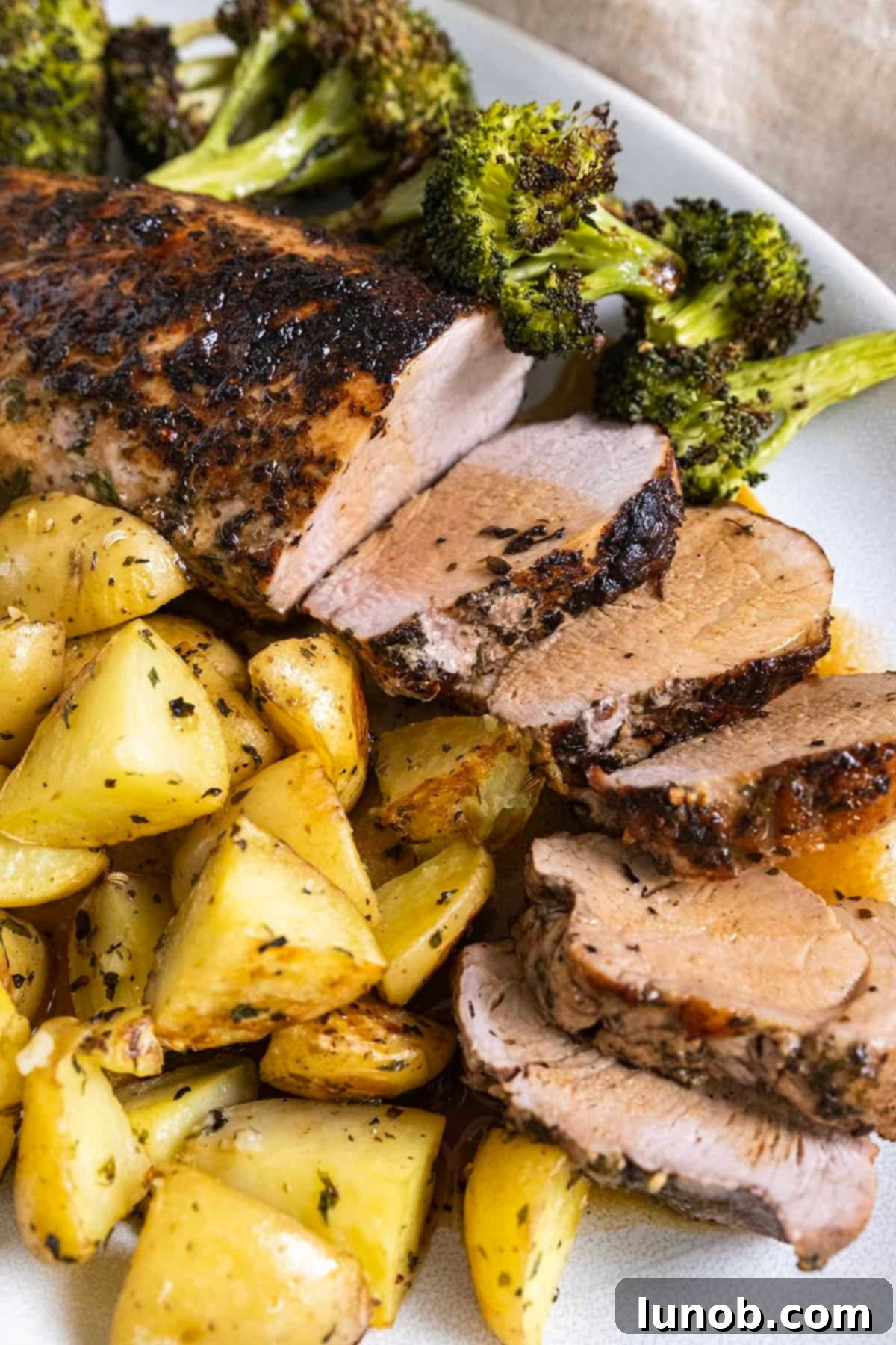 Rustic Italian Cast Iron Pork Tenderloin 2 Sliced pork tenderloin served on a plate with roasted potatoes and broccoli, drizzled with a rich garlic butter wine sauce.