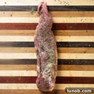 Rustic Italian Cast Iron Pork Tenderloin 4 Seasoned pork tenderloin resting on a cutting board, ready for searing.