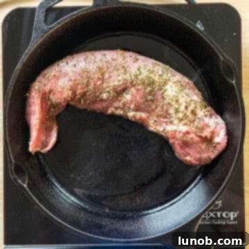 Rustic Italian Cast Iron Pork Tenderloin 5 Pork tenderloin searing in a hot cast iron pan with olive oil.