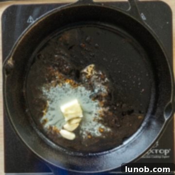 Rustic Italian Cast Iron Pork Tenderloin 8 Sautéing butter and garlic in the same cast iron pan on the stovetop.