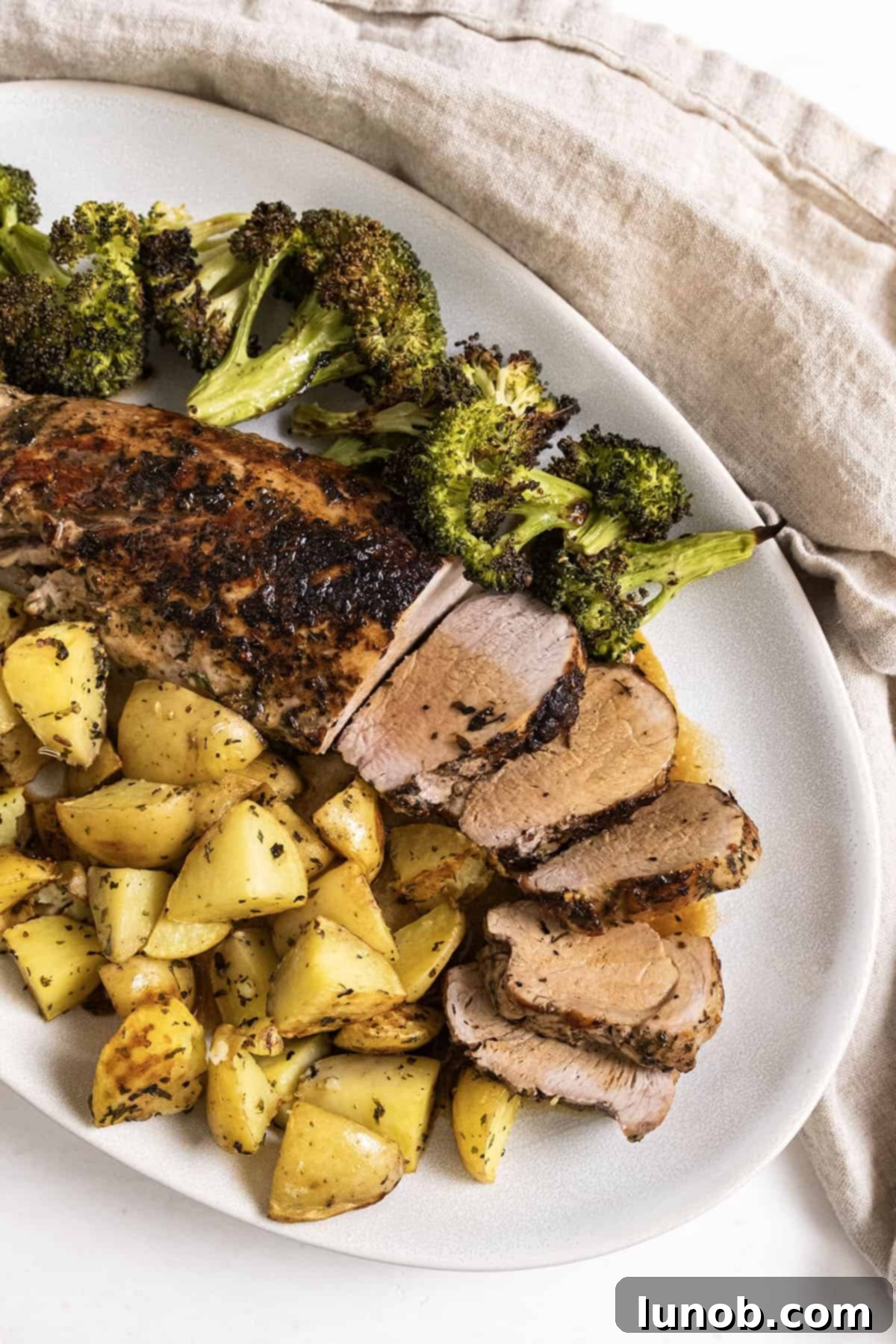 Rustic Italian Cast Iron Pork Tenderloin 10 Beautifully sliced pork tenderloin served on a plate with crispy roasted potatoes and vibrant green broccoli florets, ready to be enjoyed.