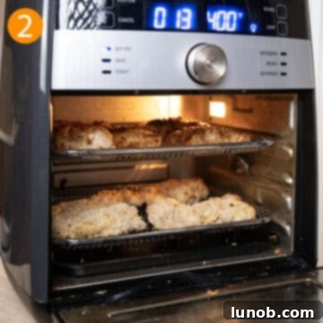Two breaded chicken thighs arranged neatly in an air fryer basket, ready for cooking.