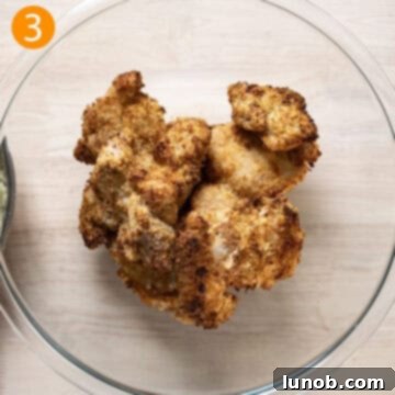 Freshly air-fried chicken thighs resting in a bowl, keeping warm while the creamy garlic sauce is prepared.