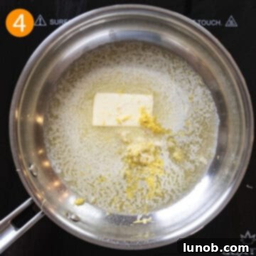 Minced garlic and fresh lemon zest simmering in melted butter in a small saucepan, releasing their aromas.