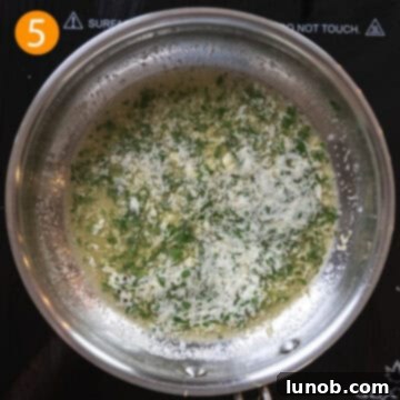 Garlic butter sauce in a pan with fresh parsley stirred in, before the addition of the creamy elements.