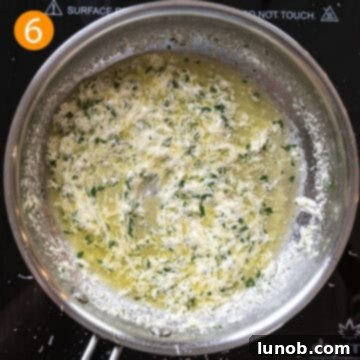 Crème fraîche being smoothly stirred into the garlic butter sauce with additional Parmesan cheese to create a rich, creamy sauce.