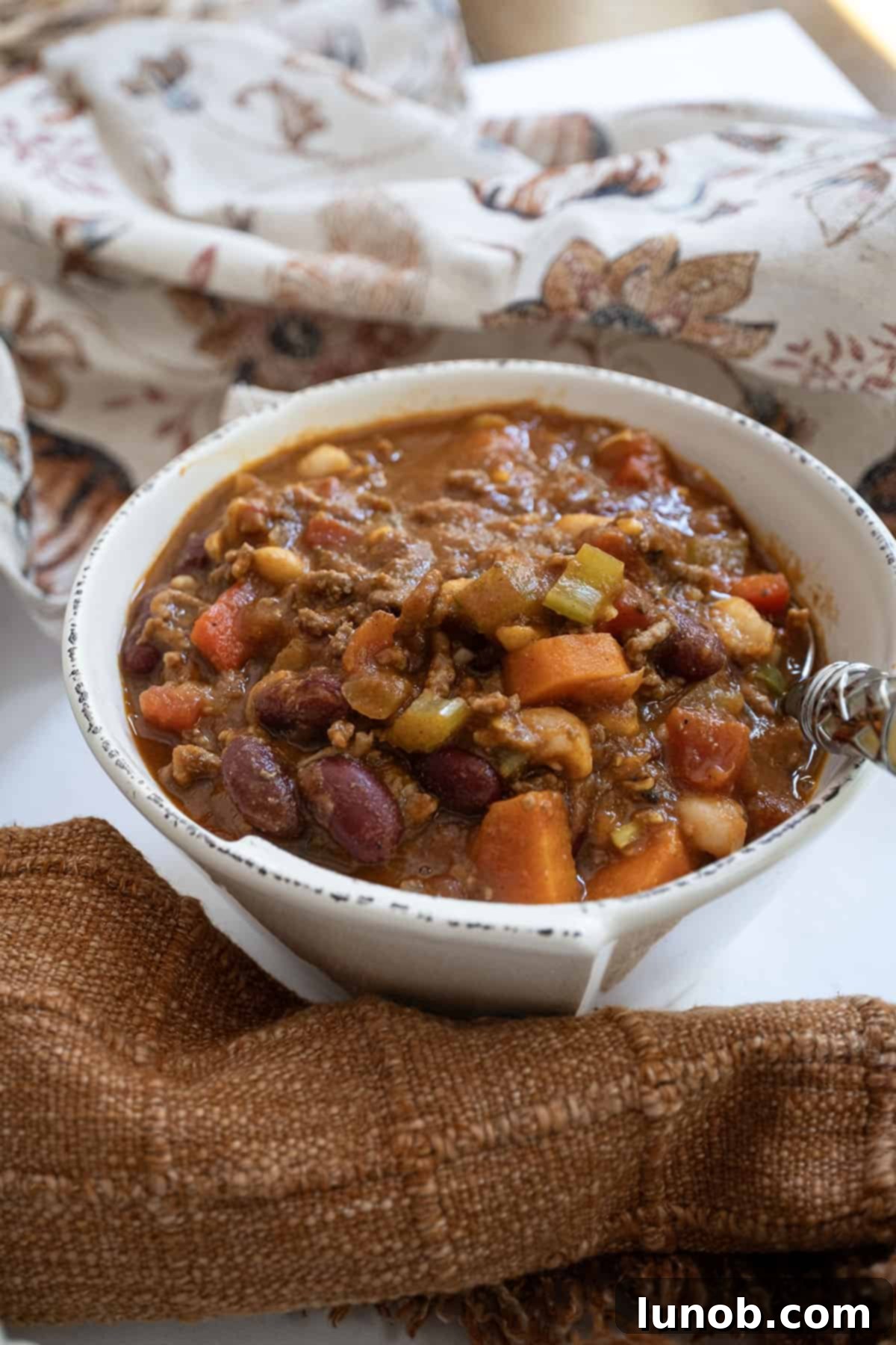 Golden Harvest White Bean Chili 2 A steaming bowl of savory white bean pumpkin chili garnished with fresh herbs, perfect for a cozy fall meal.