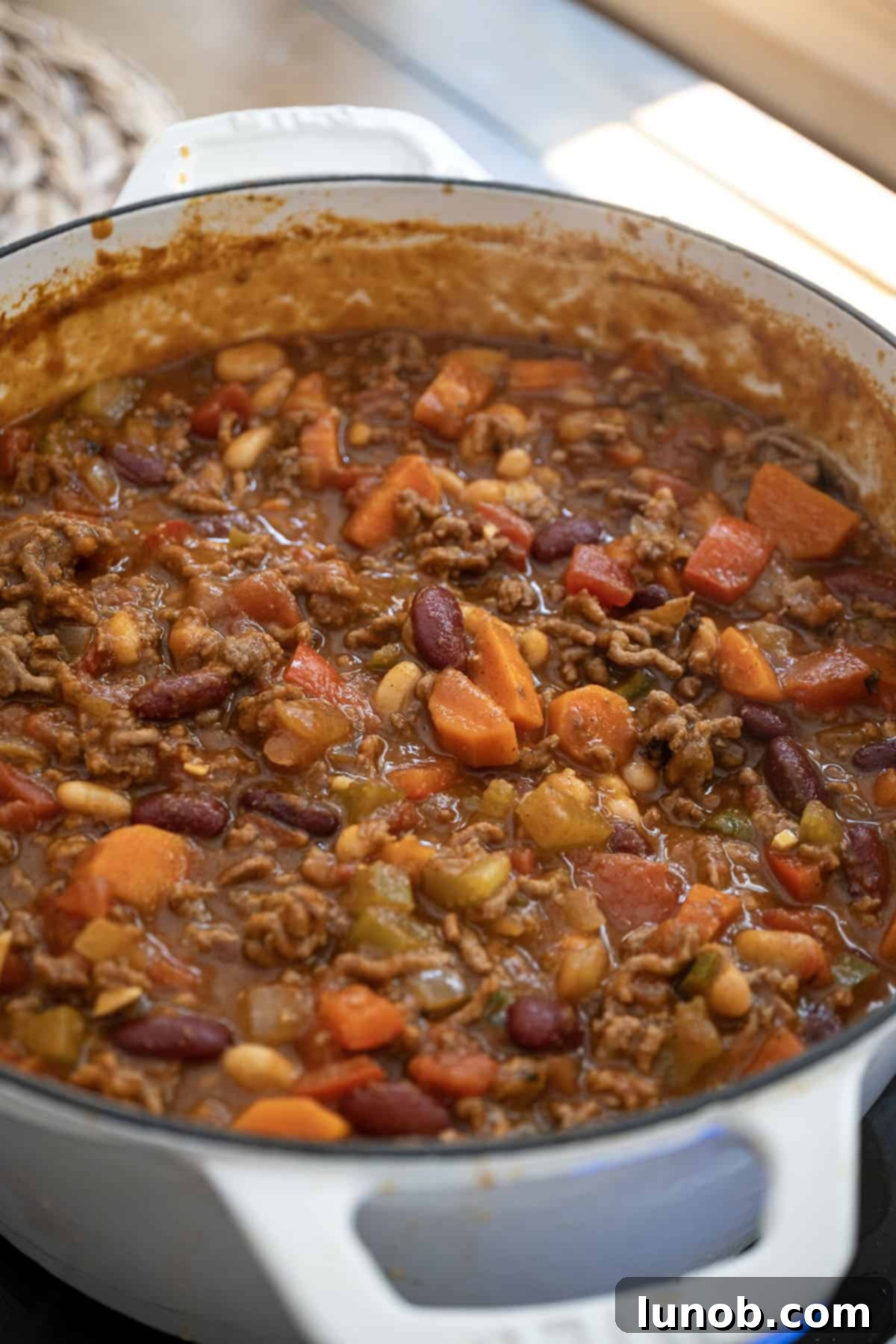 Golden Harvest White Bean Chili 12 Close-up of bubbling pumpkin chili in a Dutch oven, highlighting its rich texture and color.