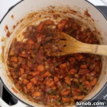 Golden Harvest White Bean Chili 7 Rich tomato paste caramelizing with sautéed vegetables in a Dutch oven, deepening the chili's flavor base.