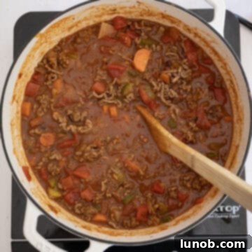 Golden Harvest White Bean Chili 9 Diced tomatoes with chiles and the browned ground beef being added to the simmering liquid in the Dutch oven.