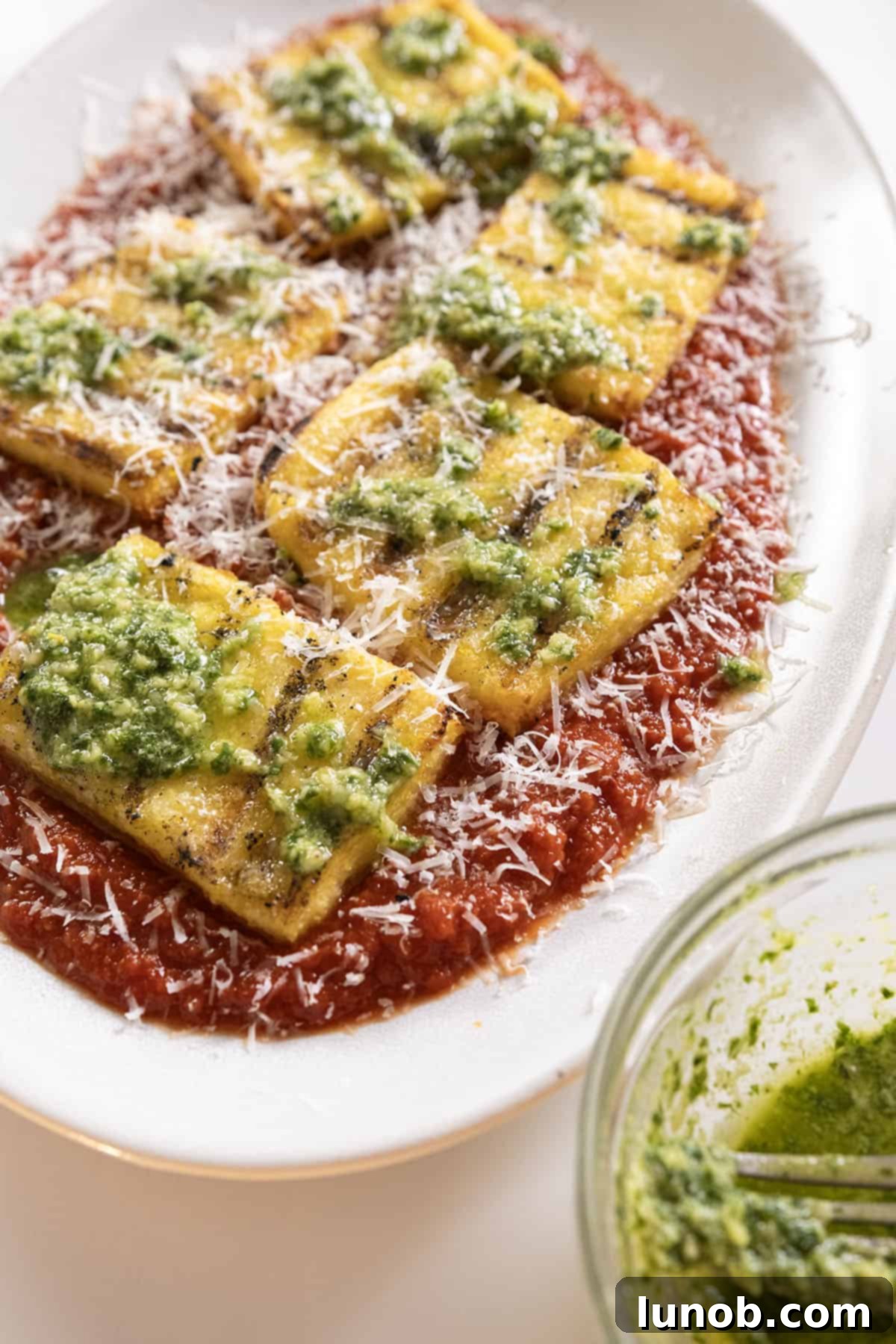 Grilled polenta on marinara topped with pesto and parmigiano.