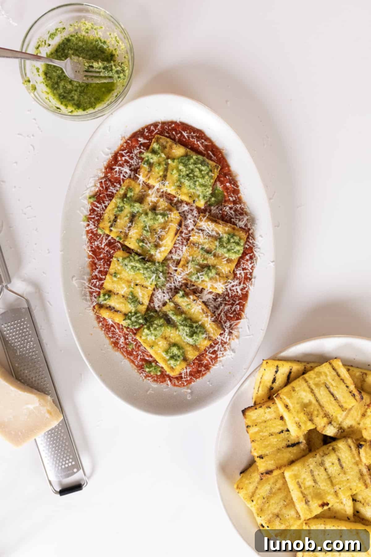 Grilled polenta on marinara topped with pesto and parmigiano.