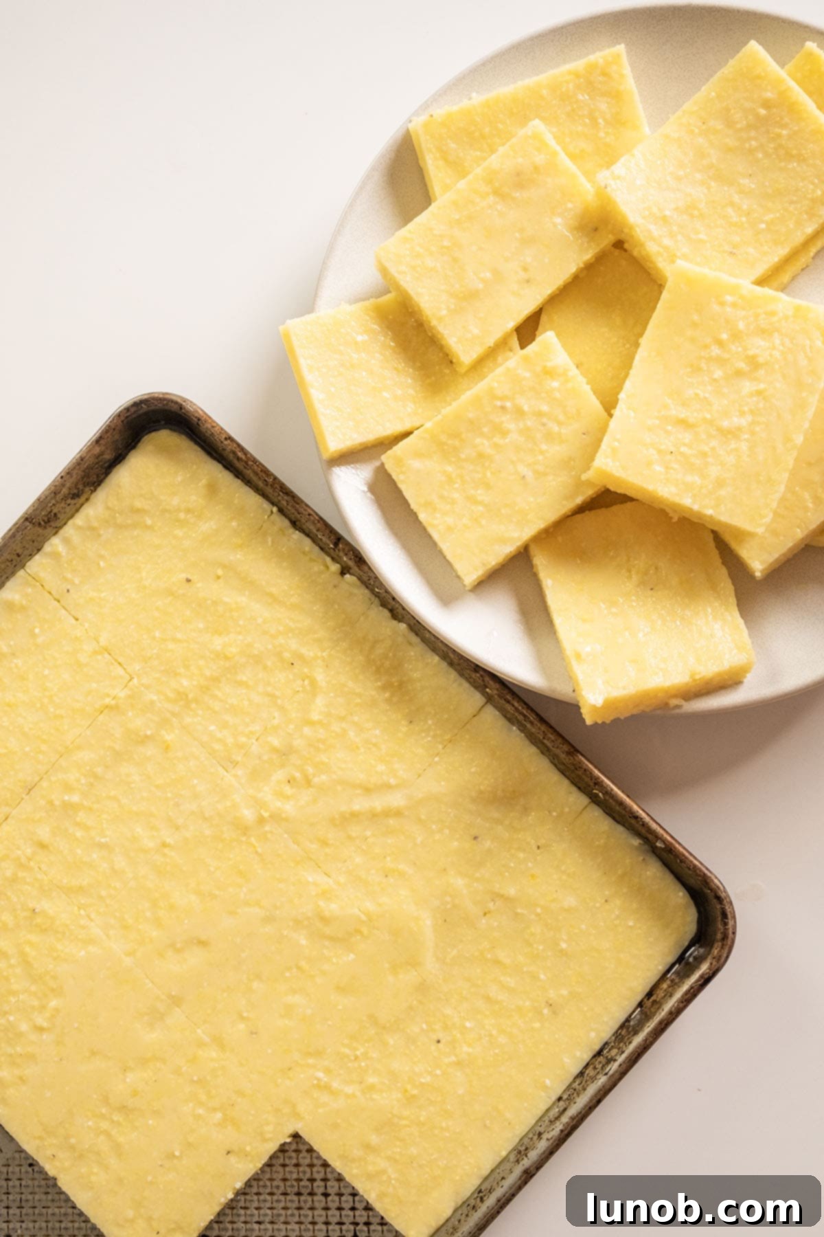 Chilled polenta cut into squares on a plate.