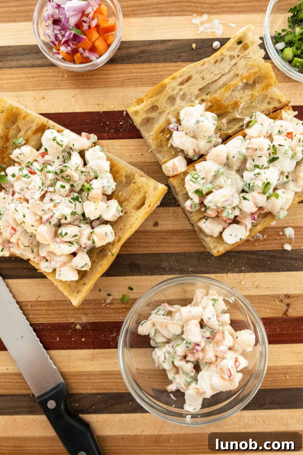 A large bowl of cold shrimp salad presented alongside two perfectly assembled shrimp salad sandwiches on toasted bread.