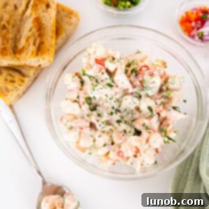 A vibrant bowl of cold shrimp salad, beautifully garnished, with a side of golden-brown toasted bread slices.