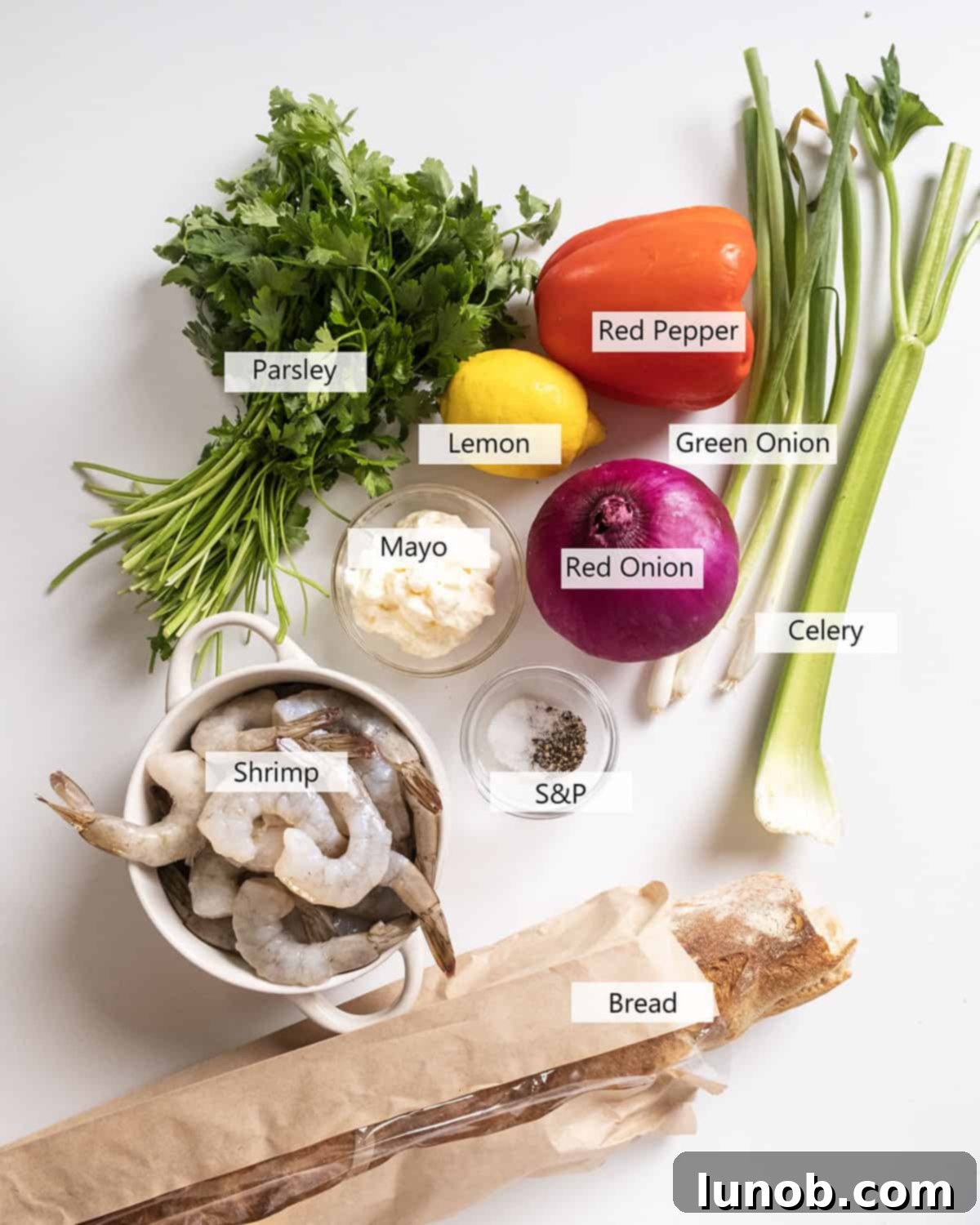 A selection of fresh, vibrant ingredients laid out for making the cold shrimp salad, including cooked shrimp, mayonnaise, and various chopped vegetables.