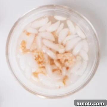 Boiled shrimp being rapidly cooled in a bowl filled with ice water to halt the cooking process.