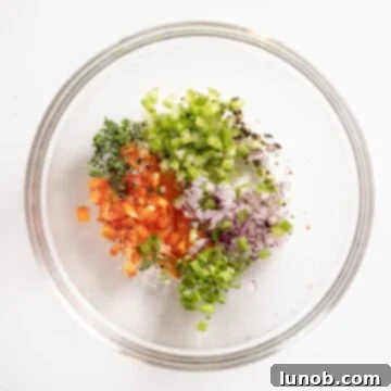 A bowl containing freshly chopped red pepper, celery, green onion, red onion, and parsley, seasoned with lemon, salt, and pepper.