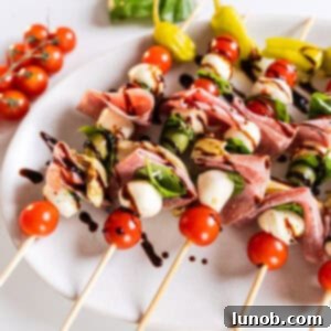 Caprese skewers on a plate drizzled with balsamic glaze.