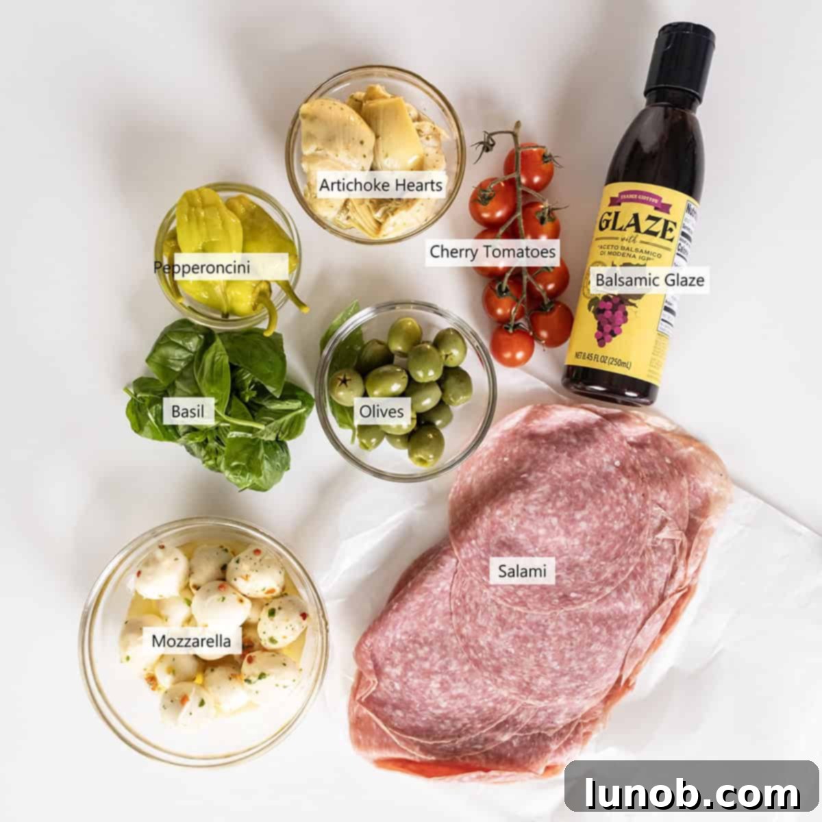 Ingredients for the Caprese antipasto skewers, including salami, mozzarella, tomatoes, and olives.