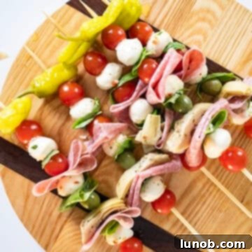 Assembling Caprese skewers with vegetables, cheese, and salami.