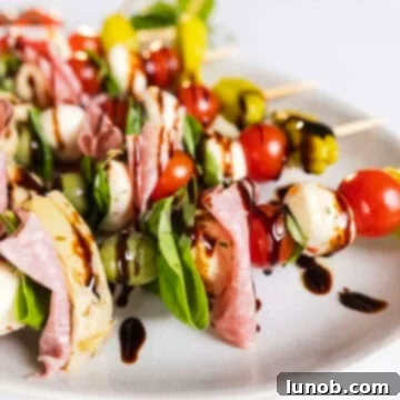 Finished Caprese skewers on a plate, drizzled with balsamic glaze.