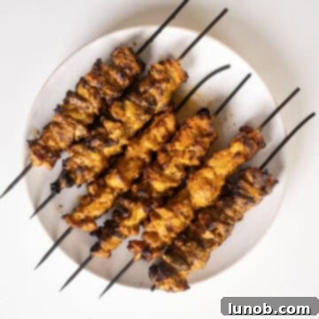 Dynamite Chicken Skewers 11 Plated Bang Bang Chicken skewers garnished with fresh lime wedges, ready to be served.