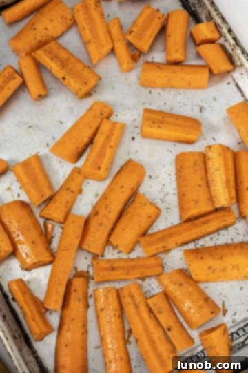 Sweet and Zesty Roasted Carrot Ginger Soup 3 seasoned carrots on baking tray ready for roasting