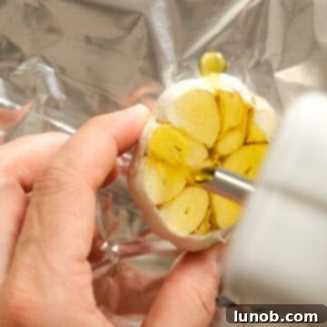 Rich Roasted Garlic and Tomato Cream Soup 4 A head of garlic, expertly prepared for roasting, with the top chopped off and drizzled with olive oil, neatly wrapped in aluminum foil.