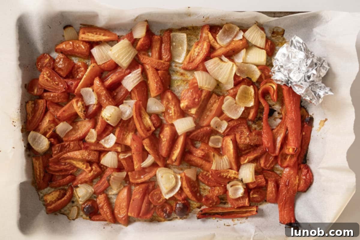 Rich Roasted Garlic and Tomato Cream Soup 7 A baking sheet filled with perfectly roasted tomatoes, onions, and red pepper, slightly softened and caramelized, having just come out of the oven, fragrant and ready for the next step.